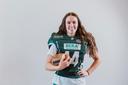 Junge Frau in Football-Montur mit Football unter dem Arm