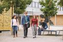Eine studierendengruppe läuft und unterhält sich vor einem gebäude.