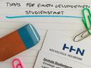 Bürountensilien, wie Bleistift, bunte Büroklammern und Radiergummie, liegen auf einem Blatt mit der Überschrift "Tipps für einen gelungenen Studienstart".