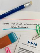 Bürountensilien, wie Bleistift, bunte Büroklammern und Radiergummie, liegen auf einem Blatt mit der Überschrift "Tipps für einen gelungenen Studienstart".