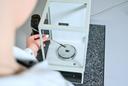 Eine Person führt eine präzise Wägung einer Substanz auf einer Laborwaage durch.