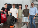 Ein Professor und mehrere Studenten stehen vor einem Rennwagen