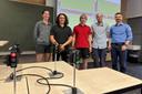 Studierende vor einer Wand, an die per Beamer das Bild einer virtuellen Straßenkreuzung projiziert ist. Im Vordergrund sind Miniaturampeln zu sehen.