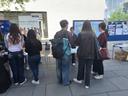 Junge Menschen stehen vor einem Stand mit Infomaterial.