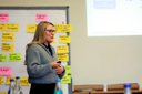 Eine Projektmitarbeiterin hält eine Präsentation vor einem Flipchart mit bunten Moderationskarten und einer projizierten Folie
