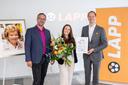 Zwei Männer und eine junge Frau (Mitte) mit einem Blumenstrauß und einer Urkunde vor Bannern der Firma LAPP bei der feierlichen Vergabe eines Stipendiums.