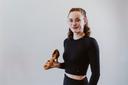 Eine junge Frau in schwarzer Sportkleidung mit einem bronzefarbenen Tanzschuh auf der rechten Hand