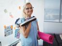 Eine Frau mit einer Yogamatte unterm Arm in einem Büro