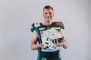 Julius Klenk - Stipendiat im Spitzensport Stipendium - lacht in seiner Football-Ausrüstung in die Kamera. Seinen Helm hält er in den Armen. 