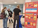 Menschen an einem Stand mit einem Rollup des Jugend hackt Lab rechts am Rand