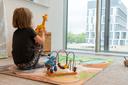 Das Foto zeigt den Eltern-Kind-Raum am Bildungscampus Heilbronn. Zu sehen ist die Rückansicht eines spielenden Mädchens von etwa 5 Jahren. Ihr Blick geht aus dem Fenster auf den Bildungscampus hinaus.