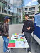 Ein junger Mann steht an einem Stand mit Infomaterial.