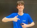 Ein junger Mann in blauem T-Shirt mit HHN-Logo lächelt in die Kamera und zeigt auf seine Gewinner-Medaille zum Titel Herrensäbel der Deutschen Hochschulmeisterschaften im Fechten