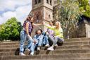 Zwei Studentinnen geben sich ein high five, während zwei weitere Studierende sich mit den beiden freuen und grinsen.  