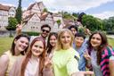 Eine Gruppe fröhlicher Studierender macht ein Selfie vor der Stadtsilhouette von Schwäbisch Hal