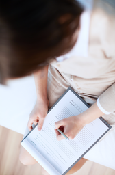 Das Bild zeigt eine weibliche Person, die Unterlagen für die Organisation von Pflegeaufgaben ausfüllt.