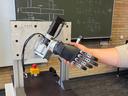 Eine Roboterhand und eine menschliche Hand führen einen Handschlag aus