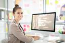 Junge Frau sitzt am Computer und programmiert. 
