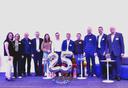 Eine Gruppe von Menschen auf einer Bühne, im Vordergrund Zahlenluftballons 25