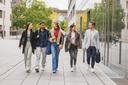 5 Studierende laufen on einer Gruppe über den Campus