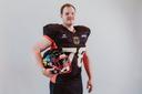 Ein Mann in Football-Kleidung mit Helm unter dem Arm