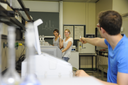 Mehrere Studierende arbeiten im Analytiklabor. Vordere Person blickt nach binten zu zwei Personen