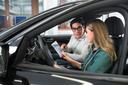 Ein Student und eine Studentin prüfen Daten mit einem Tablet vorne in einem Auto.