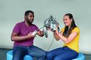 Zwei Studierende halten und betrachten einen Bausatz von Lego-Mindstorm.