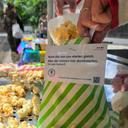 Das Bild zeigt die Nahaufnahme einer Hand, die Popcorn in eine Tüte füllt. Auf der grün gestreiften Tüte steht der Slogan für das Vielfaltsthema "Soziale Herkunft"