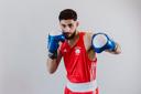 Ein junger Mann mit rotem Trickot und blauen Boxhandschuhen in Boxsposition